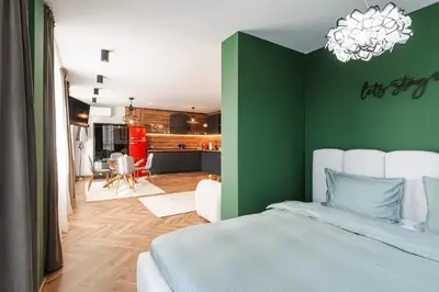 a green bedroom with a bed and a kitchen at Уютно Студио Verde Suites 33 in Blagoevgrad