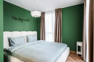 a green bedroom with a bed and a chandelier at Уютно Студио Verde Suites 33 in Blagoevgrad