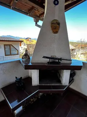an outdoor oven with a large bell on a balcony at Апартаменти село Баня in Banya