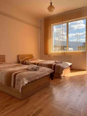 a bedroom with two beds and a large window at Slavveykovs Apartment in Sofia