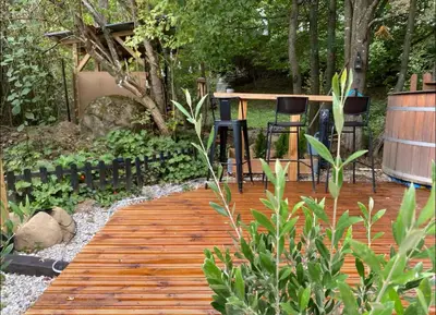 a wooden walkway in a garden with two chairs at VILLA INBAR - Village house on the river in Boykovets