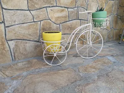a white bicycle with two yellow buckets next to a stone wall at Къща Томови in Devin