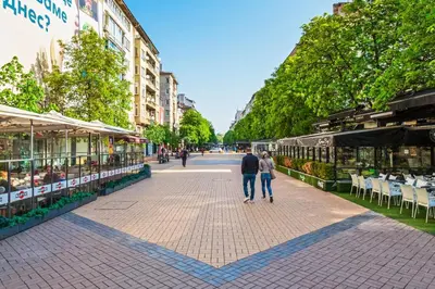 a man and woman walking down a street with tables and chairs at Casa Dolce far niente , in Blue, PARKING in Sofia