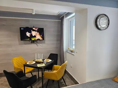 a dining room with a table and chairs and a clock at Continental studios 1 in Sofia