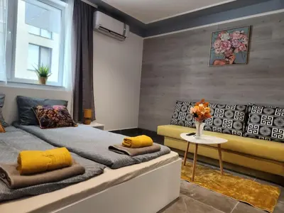 a bedroom with a bed with yellow pillows and a table at Continental studios 1 in Sofia