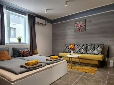 a bedroom with a large bed and a yellow couch at Continental studios 1 in Sofia