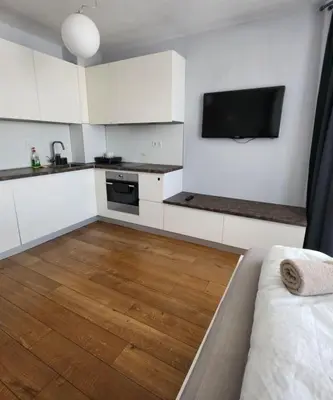 a kitchen with white cabinets and a television on the wall at Mallside Residences in Sofia