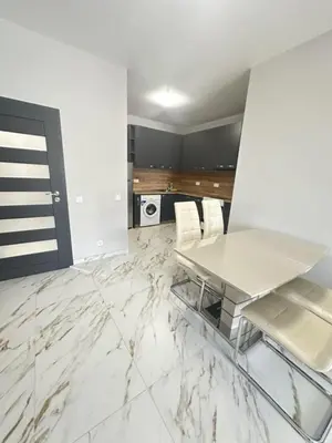 a white kitchen with a glass table and white chairs at No Remorse Tower & private parking in Sofia