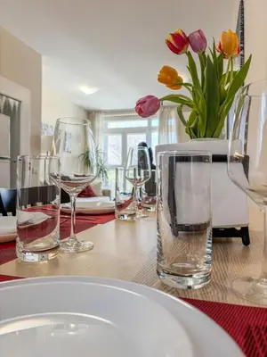 a table with wine glasses and a vase of flowers at Scandi Suite Business & Leisure in Sofia