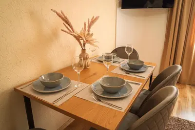 a wooden table with chairs and plates and wine glasses at Azuri in Sandanski