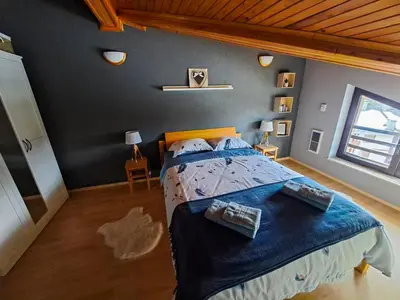 a bedroom with a large bed with a blue blanket at Nordic Sunset Retreat in Pamporovo