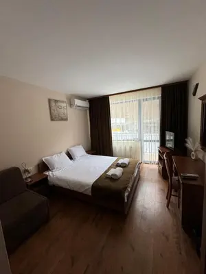 a bedroom with a bed and a couch and a window at Къща за гости Стефани in Devin