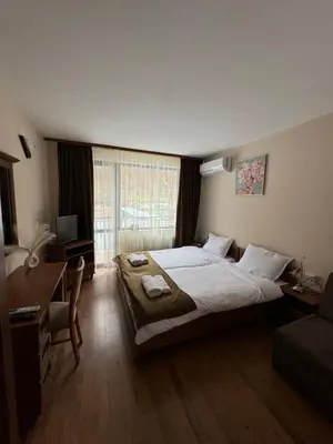 a bedroom with a bed and a desk and a window at Къща за гости Стефани in Devin