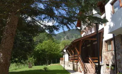 a building with a tree and a mountain in the background at Ловна резиденция ДЛС Извора in Devin