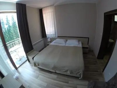a bedroom with a bed and a large window at Ивелия Къща за гости in Dospat