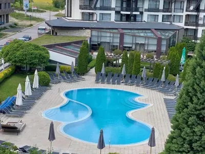 a swimming pool at a hotel with chairs and umbrellas at Cozy SPA Retreat with free Bottle of Wine in Aspen Golf in Razlog