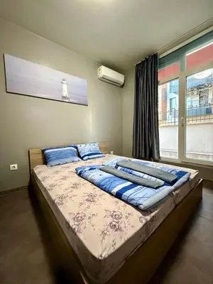 a bedroom with a bed with blue pillows and a window at Maxi studio & private parking included in Sofia