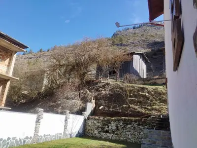 a house with a stone wall and a hill at ADVENTURE apartments Trigrad in Trigrad
