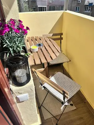 a table and chair on a balcony with flowers at Artistic and cozy apartment in the center of Sofia in Sofia