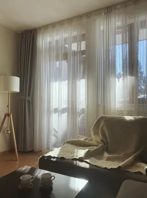 a bedroom with a bed and a window with cups on a table at Gardenia Apartment Pamporovo in Pamporovo