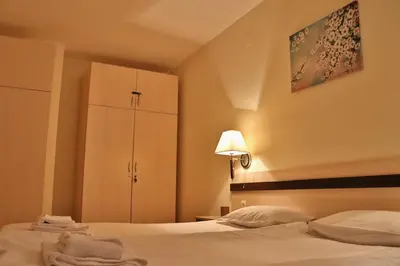 a bedroom with a bed with white sheets and a cabinet at Gardenia Apartment Pamporovo in Pamporovo