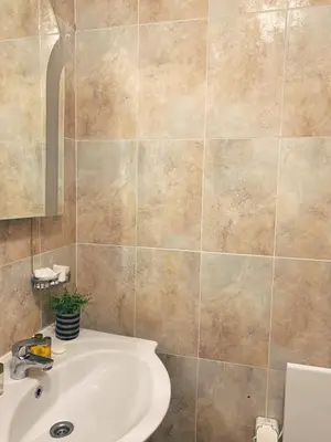 a bathroom with a sink and a tiled wall at Gardenia Apartment Pamporovo in Pamporovo