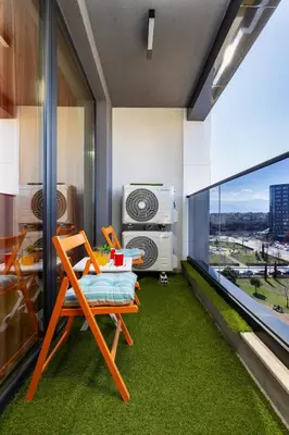 a room with a balcony with green carpet and a chair at City Park flat near to Medical University in Plovdiv