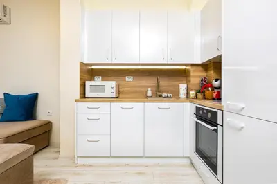 a kitchen with white cabinets and a microwave at City Park flat near to Medical University in Plovdiv