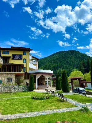 a building with benches in the grass in front of it at Trigrad hills in Trigrad
