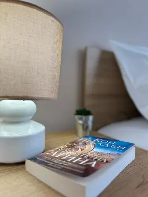 a book sitting on a table next to a bed at Rea Elita - Fresh and Modern Studio in Sofia