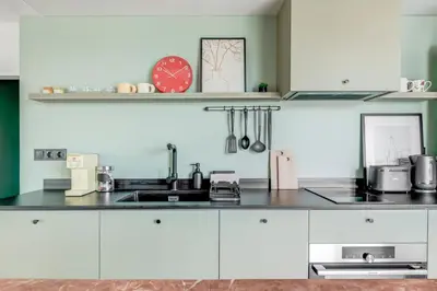 a kitchen with white cabinets and a clock on a shelf at Quiet Elegance in Sofia Center in Sofia