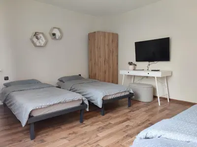 two beds in a room with a desk and a television at Тристаен апартамент in Elin Pelin