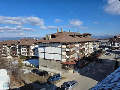 an apartment building with cars parked in a parking lot at KS Gondola point apartment in Bansko