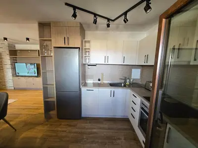 a kitchen with white cabinets and a black refrigerator at KS Gondola point apartment in Bansko