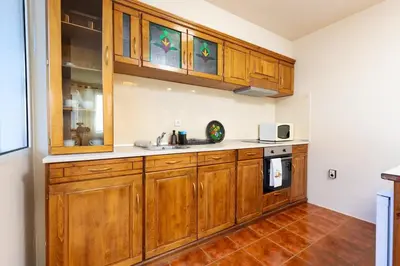 a kitchen with wooden cabinets and a tile floor at Stancho's House 3BR apartment close to OLD TOWN & KAPANA district in Plovdiv