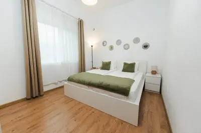 a white bedroom with a bed and a window at Apartment Velik in Sandanski