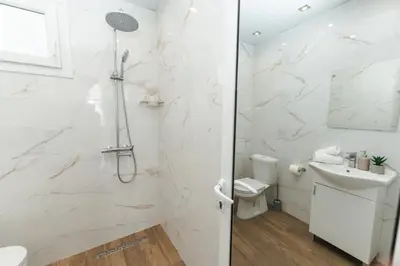 a white bathroom with a shower and a sink at Apartment Velik in Sandanski