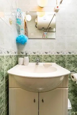 a white sink in a bathroom with green tiles at Quiet apartment near the center by Flat Mаnager in Plovdiv