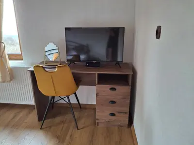 a desk with a television and a chair in a room at Капсъзовата къща in Leshten