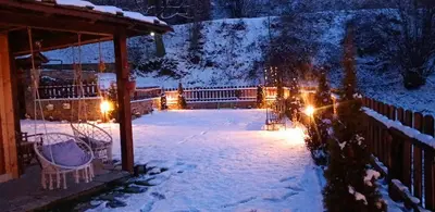 a snow covered yard with a gazebo with lights at Капсъзовата къща in Leshten
