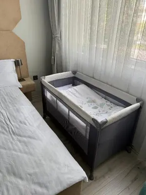 a baby bed in a bedroom with a window at ElenartLux - Baby Cot - Pets Allowed - Free Parking & Fast Wi-Fi in Plovdiv