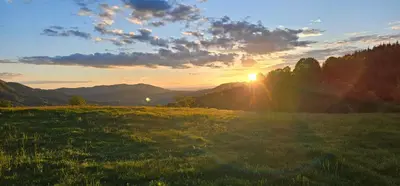 a field with the sun setting in the mountains at Комплекс Арда in Arda
