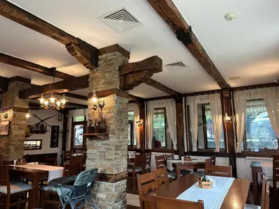 a dining room with tables and a stone fireplace at Гнездото на Гълъба in Ostrets