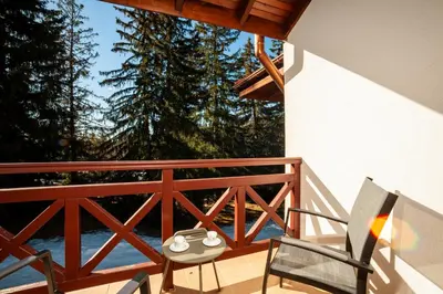 a porch with two chairs and a table on a balcony at Гнездото на Гълъба in Ostrets