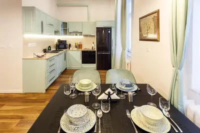 a dining room with a table and chairs and a kitchen at Klimt's Puzzle Suite in Sofia