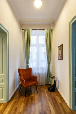 an orange chair in a room with a window at Klimt's Puzzle Suite in Sofia