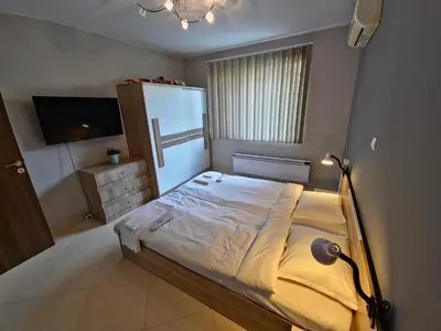 a bedroom with a large bed and a television at Къща за гости Спирката in Spatovo