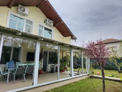a house with sliding glass doors and a patio at Къща за гости Спирката in Spatovo
