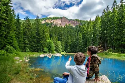 two children sitting on a rock looking at a lake at Ski & View Pamporovo Apartment in Smolyan