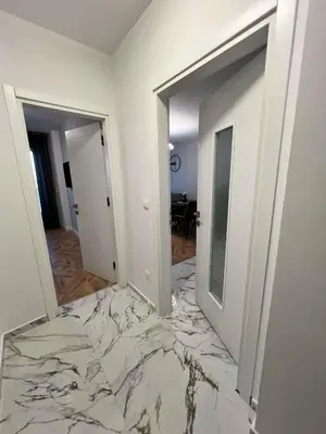 a white room with a marble floor and two doors at City lux apartment in Plovdiv